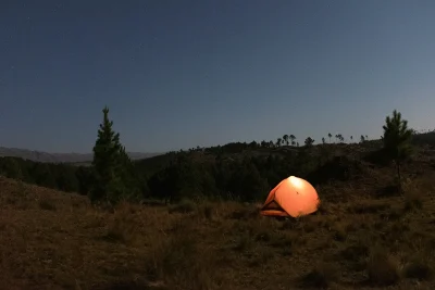Orange tent set up at sunset for sleeping outside in summer